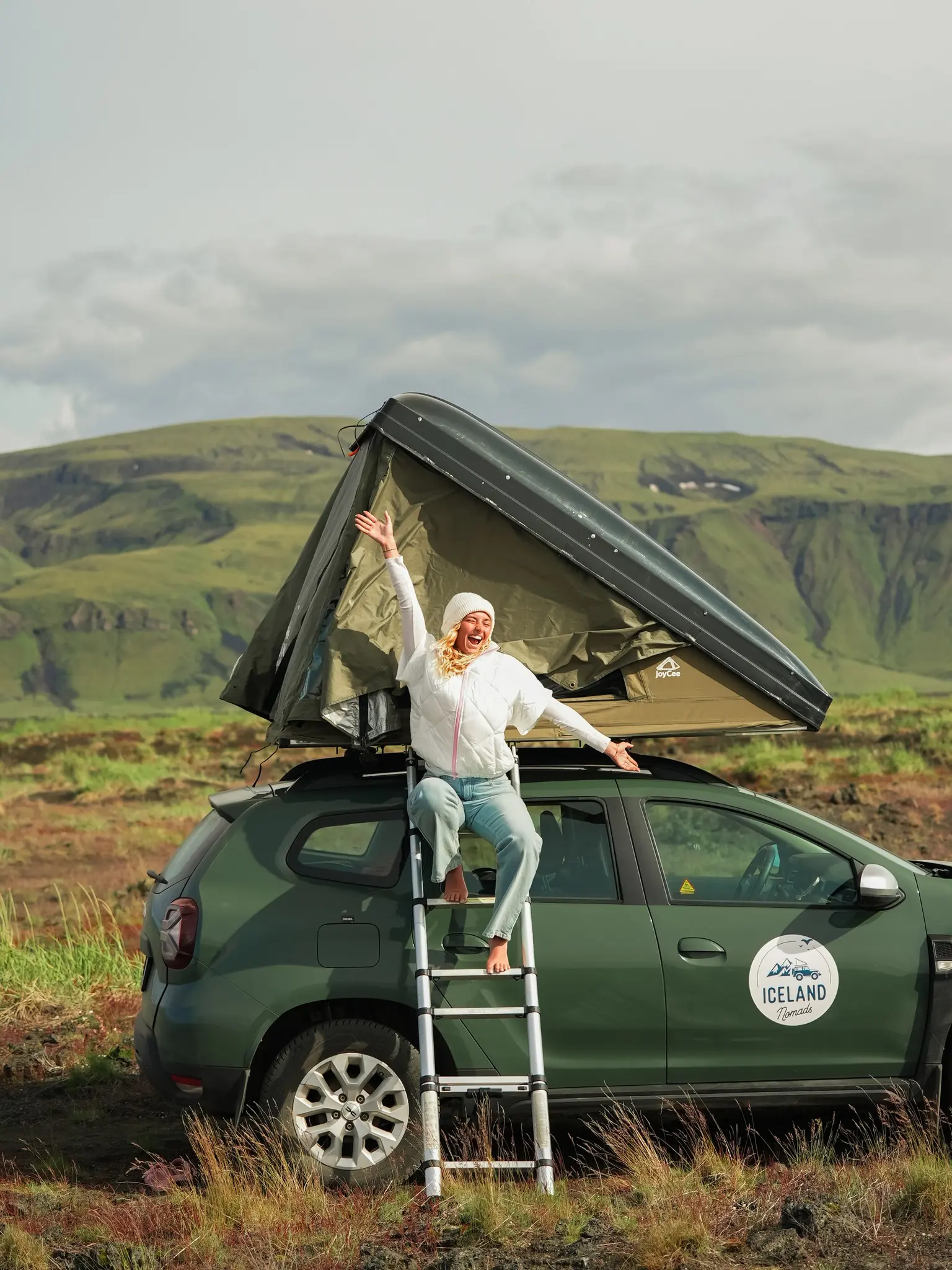woman on ladder of rooftop tent on car in Iceland