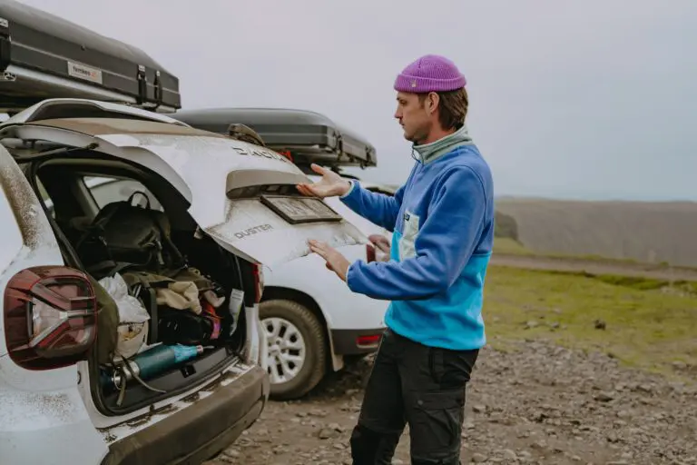 man with purple beanie opening car trunk in Iceland