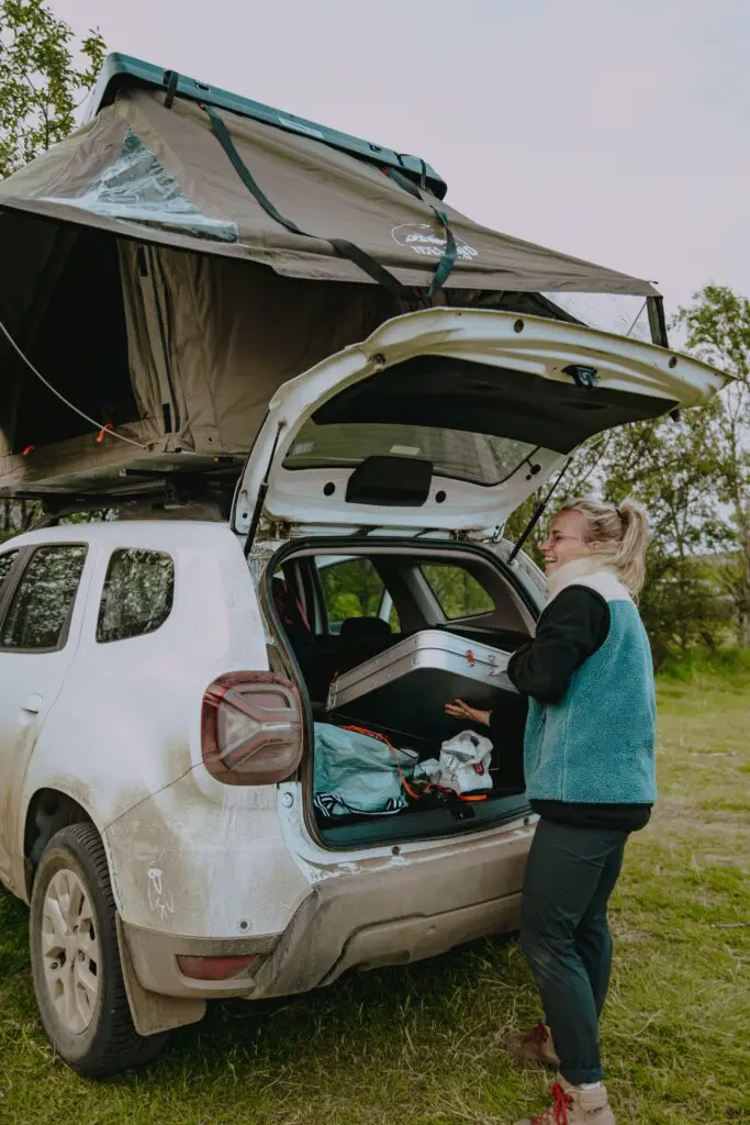 woman packing car with rooftop tent in Iceland