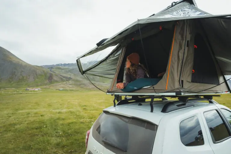 woman relaxing in rooftop tent on car in Icelandic landscape