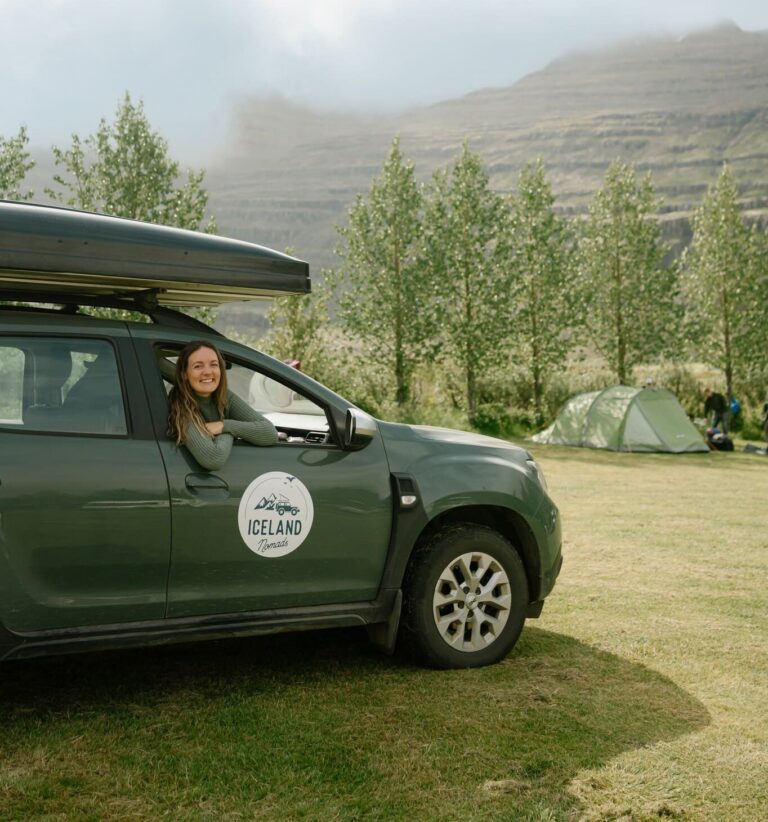 woman smiling from a green camper van in Iceland